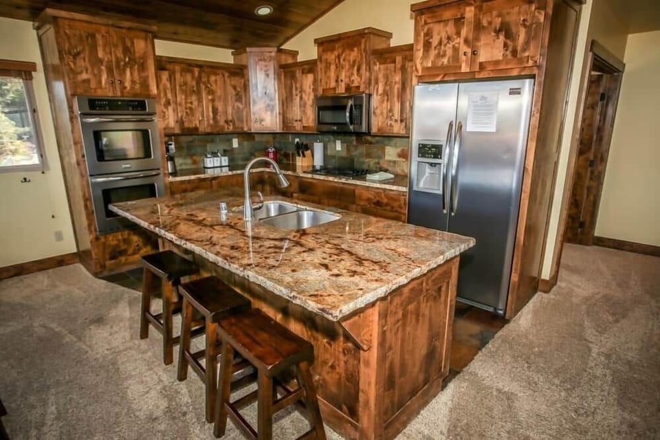 This modern kitchen features stunning wooden cabinetry, stainless steel appliances, and convenient dining.