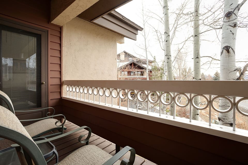 Unwind on your private balcony with charming mountain lodge views and peaceful aspen trees framing the scene.