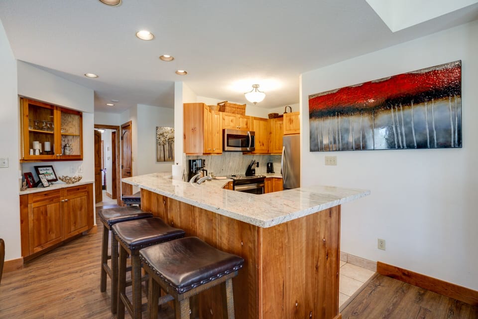 Your fully-equipped kitchen features warm wood cabinetry, granite countertops, and a breakfast bar perfect for morning coffee or casual meals.