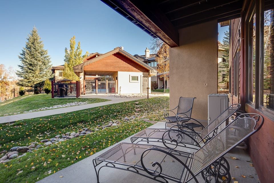 Relax on your private patio with elegant loungers overlooking the peaceful neighborhood and autumn trees.