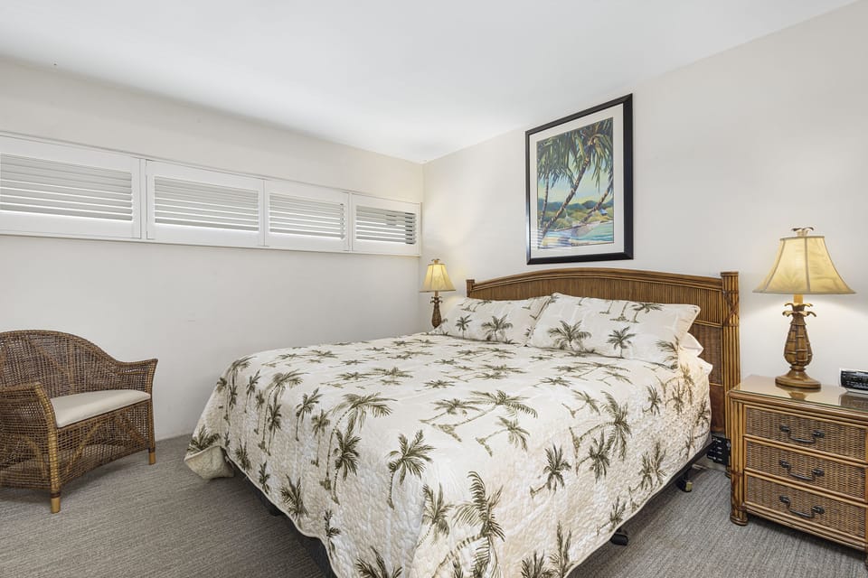 Slip into your tropical retreat with a cozy bed dressed in palm-patterned linens, warm bedside lighting, and soothing coastal artwork that invites you to unwind and dream of island breezes.