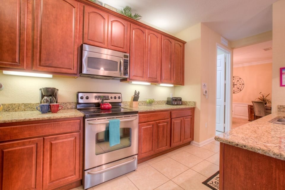 Step into our fully equipped kitchen of the condo in Orlando - Designed to inspire your inner chef with its modern amenities and sleek design - Admire the architectural charm of our wooden work in the kitchen - Plenty of storage space