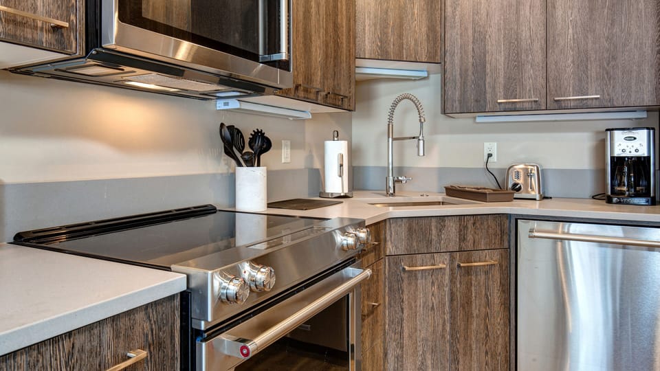 Prepare meals in our fully equipped kitchen, featuring a large island with bar seating, modern stainless steel appliances, and a stylish two-tone design. All the essentials for a great stay.