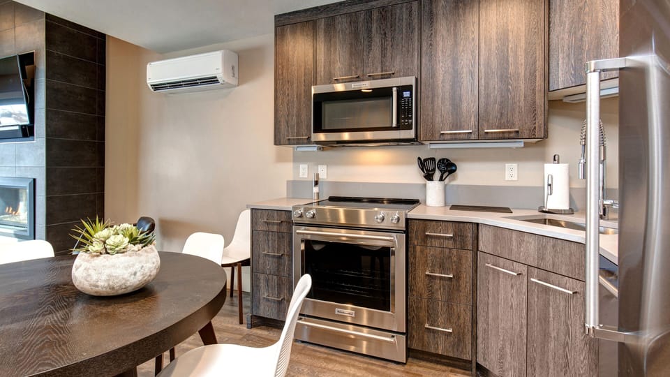 Prepare meals in our fully equipped kitchen, featuring a large island with bar seating, modern stainless steel appliances, and a stylish two-tone design. All the essentials for a great stay.