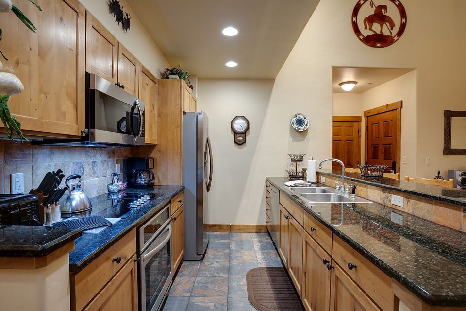 Cook your favorite meals in this spacious kitchen featuring granite counters, stainless appliances, and rustic wood cabinets.