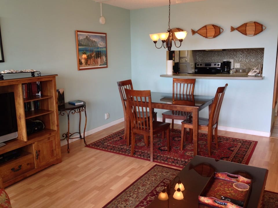 Step into your inviting open-concept living and dining space, where warm wood tones meet coastal charm. Gather around the dining table for meals while the fully-equipped kitchen awaits your culinary adventures.