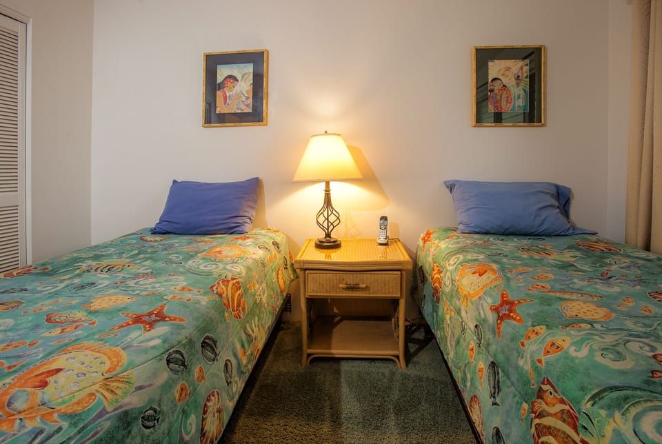 Unwind in your cheerful twin bedroom, where tropical bedding and warm lighting create a relaxing coastal retreat after a day of adventure.