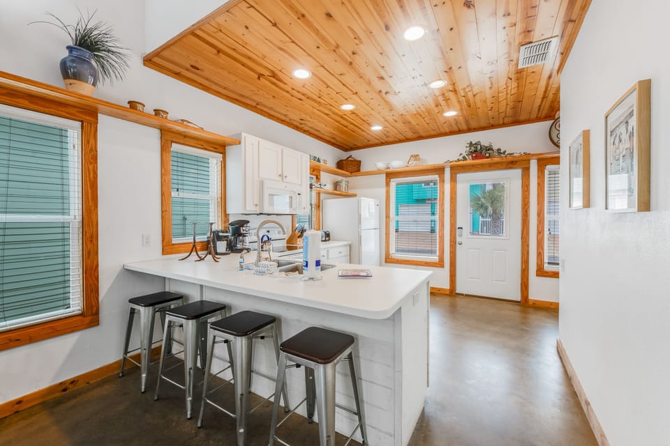 Gather around your bright kitchen island with warm wood details, where morning coffee and evening conversations feel naturally at home.