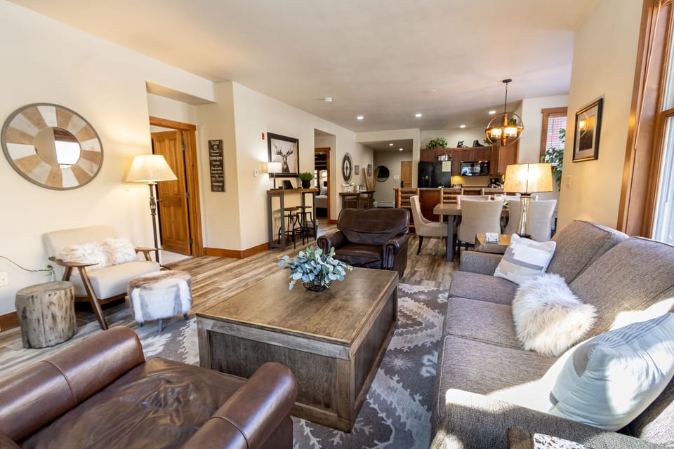 Sink into plush sofas by the fireplace in this inviting open-concept space, where rustic charm meets modern comfort for your perfect mountain retreat.