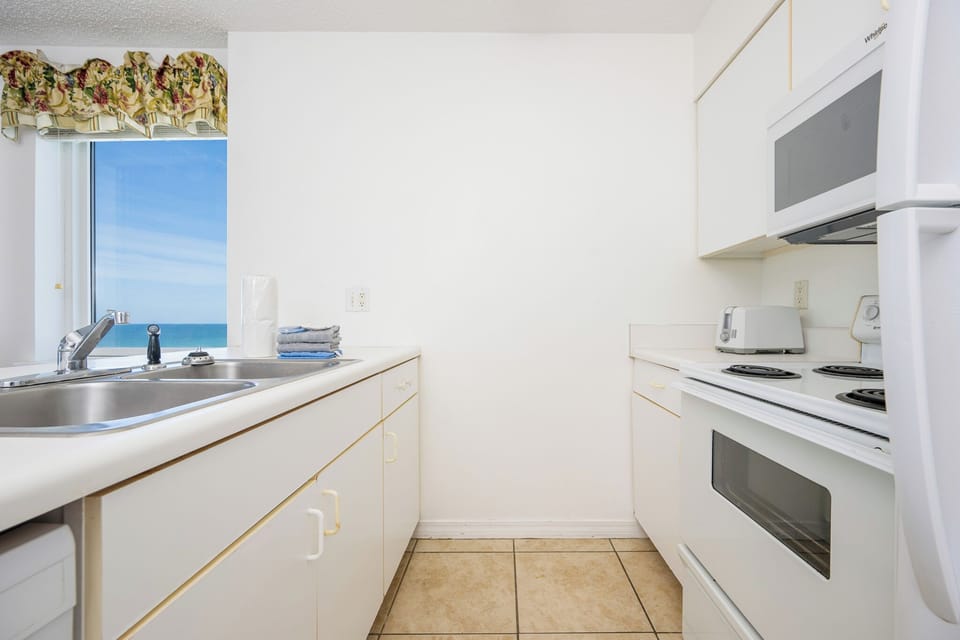 This kitchen features white cabinetry, essential appliances, and a convenient layout for preparing meals