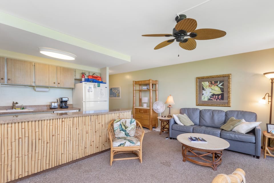 Relax in your beachy open living area with tropical fan, comfy seating, and well-equipped kitchenette—perfect for easy coastal getaways.