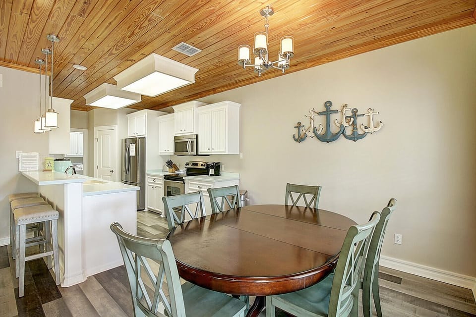 Your coastal kitchen features warm wood ceilings, crisp white cabinets, and a dining table perfect for family gatherings.