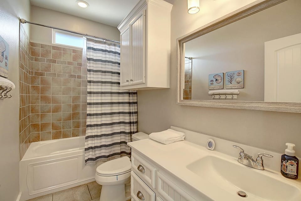 Unwind in your private bathroom featuring a relaxing soaking tub, walk-in shower with beautiful tile work, and thoughtful coastal touches throughout.