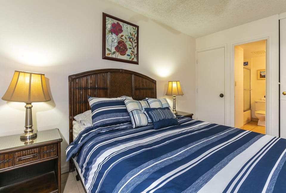 Your restful bedroom features a plush queen bed with nautical-inspired linens, warm bedside lighting, and an en-suite bathroom—everything you need for a comfortable stay.