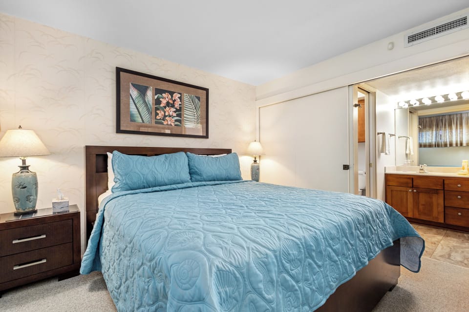 Sink into plush quilted bedding and coastal-inspired décor in your serene bedroom retreat, featuring elegant tropical artwork and a spa-like ensuite for ultimate relaxation.