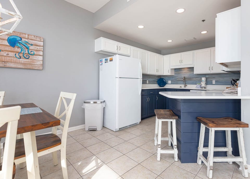 Bright kitchen featuring white cabinetry, a blue accent wall, and a breakfast bar with rustic stools for casual dining