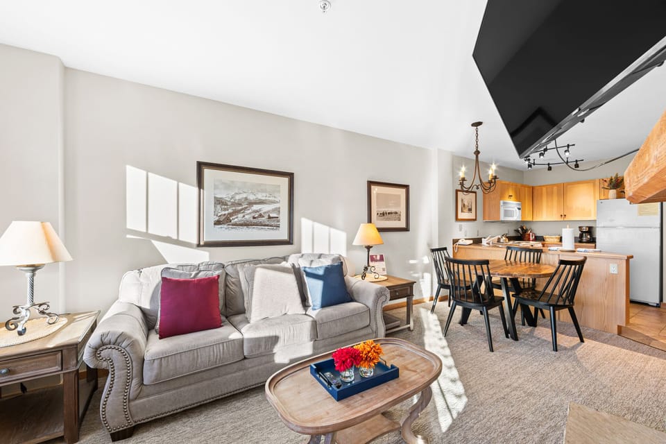 Settle into your cozy living room where natural light streams across plush sofas and colorful pillows, creating the perfect retreat after mountain adventures.