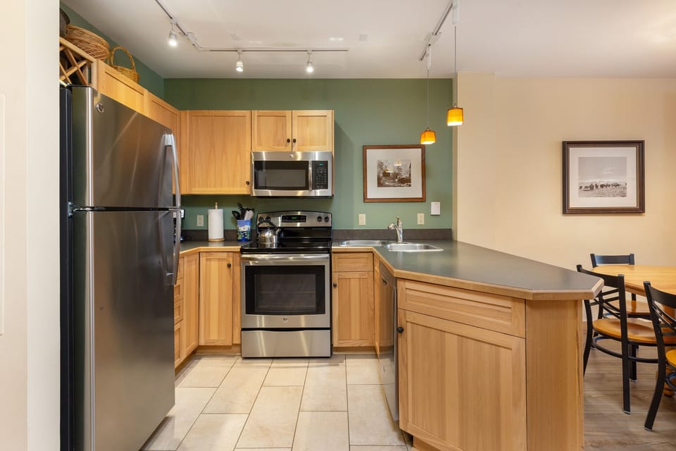 Your fully equipped kitchen features stainless steel appliances, warm wood cabinets, and granite countertops perfect for preparing meals.