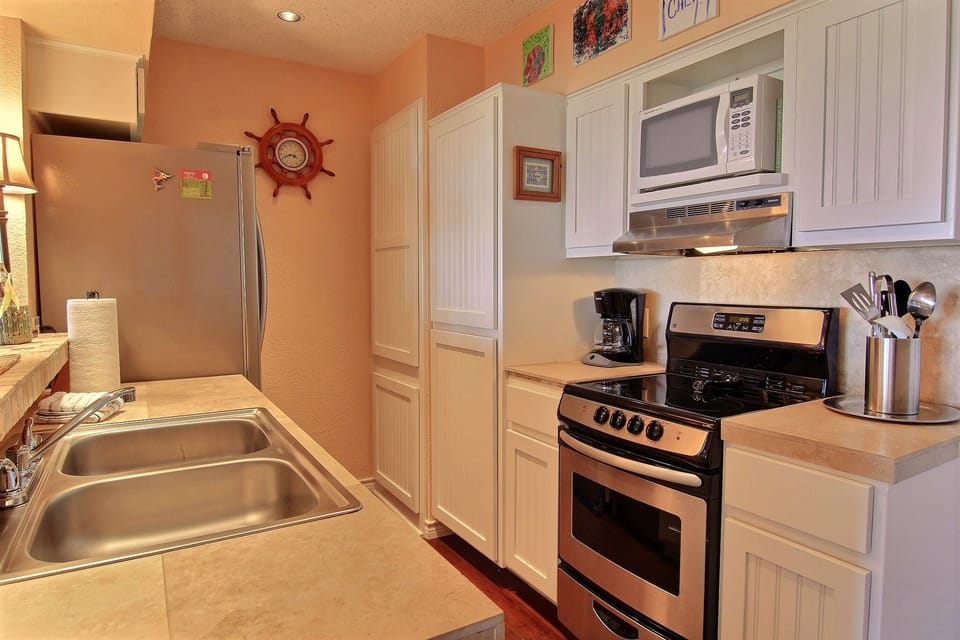 Your fully equipped kitchen awaits with stainless steel appliances, white cabinetry, and nautical touches that create a welcoming coastal vibe for your cooking adventures.