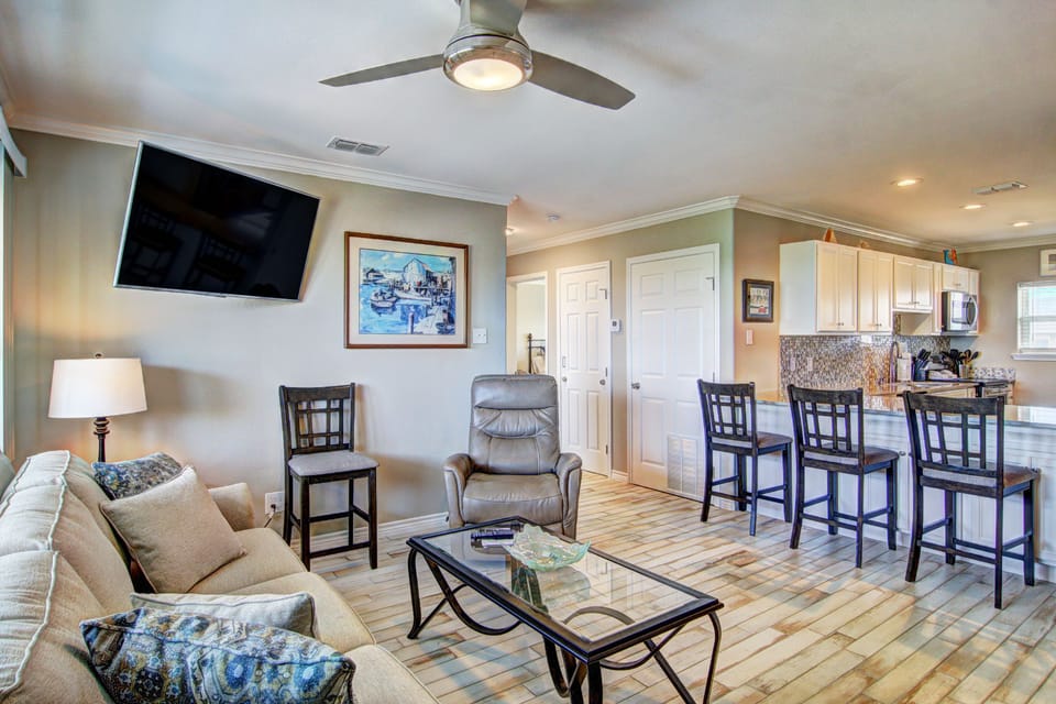 Relax in your open-plan living space featuring a plush sofa, entertainment center, and breakfast bar that flows seamlessly into the kitchen.