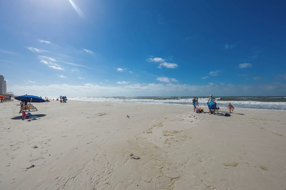 Relax on the soft sand while watching families play and splash in the waves, just steps from your beachfront rental