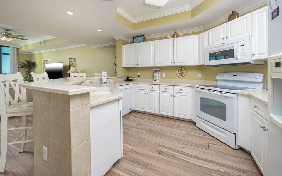 Prepare meals in this kitchen with sleek cabinetry, white appliances, and spacious countertops