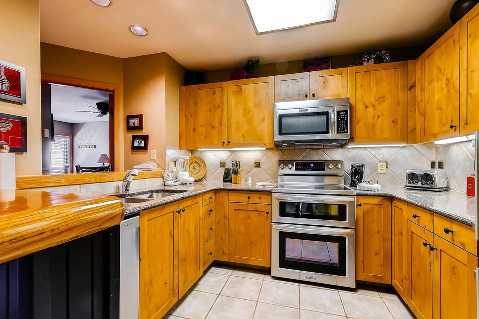 Your fully equipped kitchen awaits with warm wood cabinets, granite countertops, and modern appliances for memorable home-cooked meals.