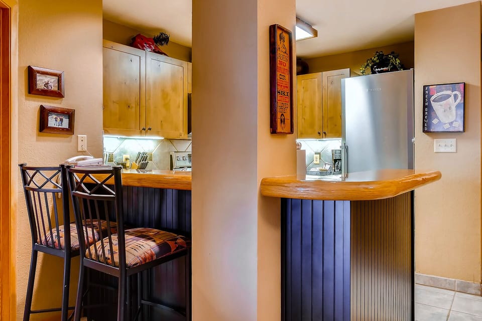 Your fully equipped kitchen features warm wood counters, stainless steel appliances, and cozy breakfast bar seating perfect for morning coffee.