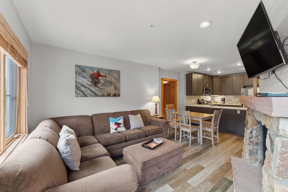 Relax in your modern mountain retreat with a cozy sectional sofa, stone fireplace, and full kitchen perfect for preparing meals after your adventures.