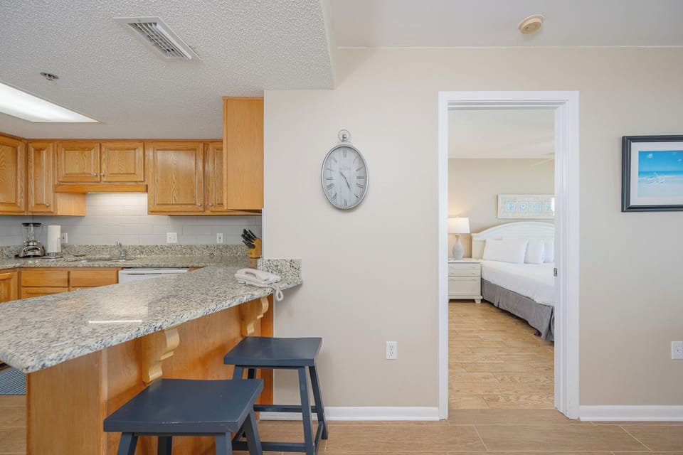 The guest suite welcomes restful nights on a king bed beneath soft lamp glow and coastal art