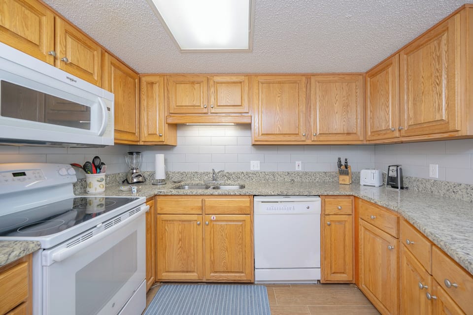 Smooth granite counters and wooden cabinetry create a warm kitchen space where you prepare family meals with ease