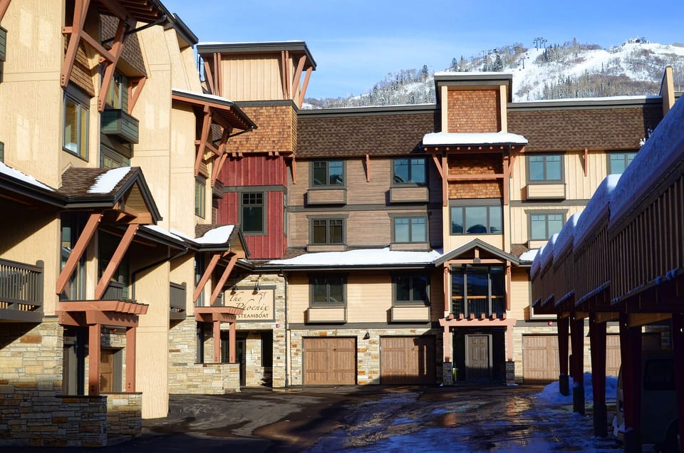 Mountain lodge buildings with snow-dusted roofs nestled against dramatic ski slopes, creating an authentic alpine village atmosphere.