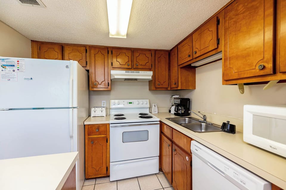 This kitchen features wooden cabinetry, essential appliances, and a welcoming atmosphere for preparing meals
