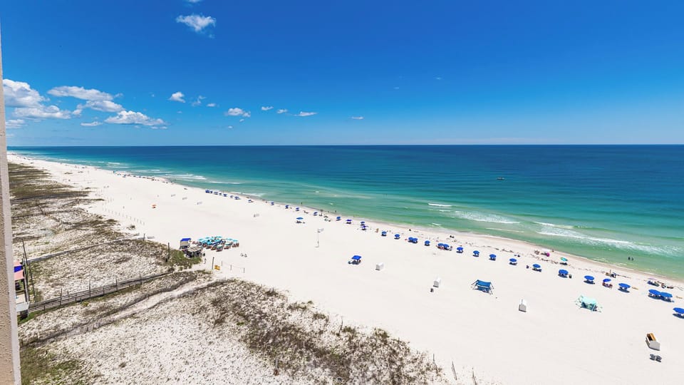 Endless turquoise waters stretch beneath a wide blue sky as you gaze across the beach front coast
