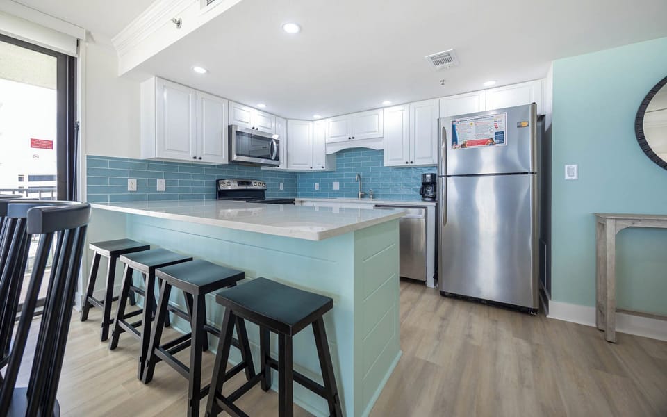 Soft blue tiles brighten the kitchen while you sip morning coffee at the breakfast bar stools