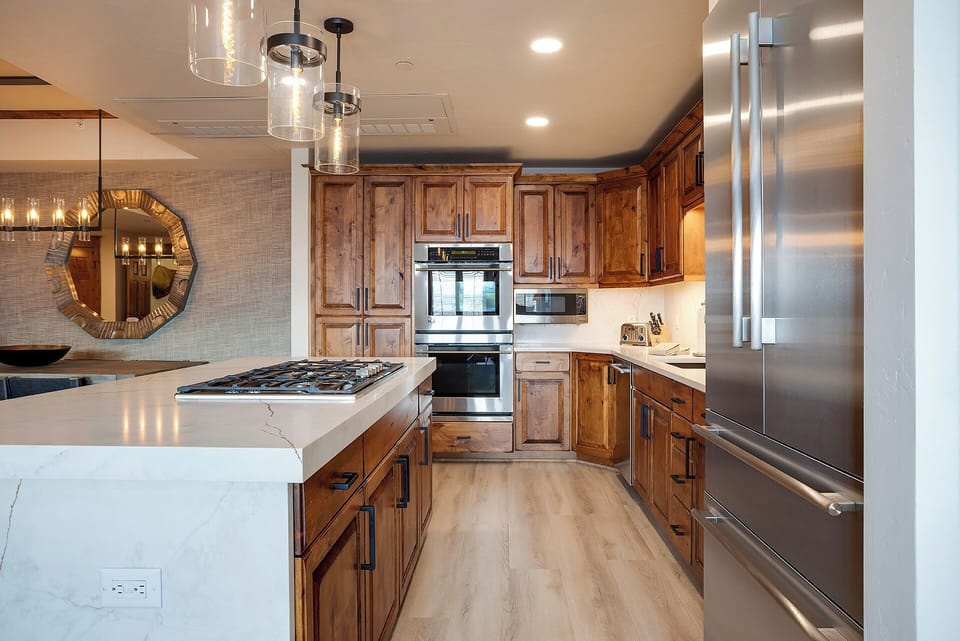 Picture yourself preparing meals in this spacious kitchen, where warm wood cabinetry meets sleek stainless steel appliances and elegant marble countertops invite culinary creativity.