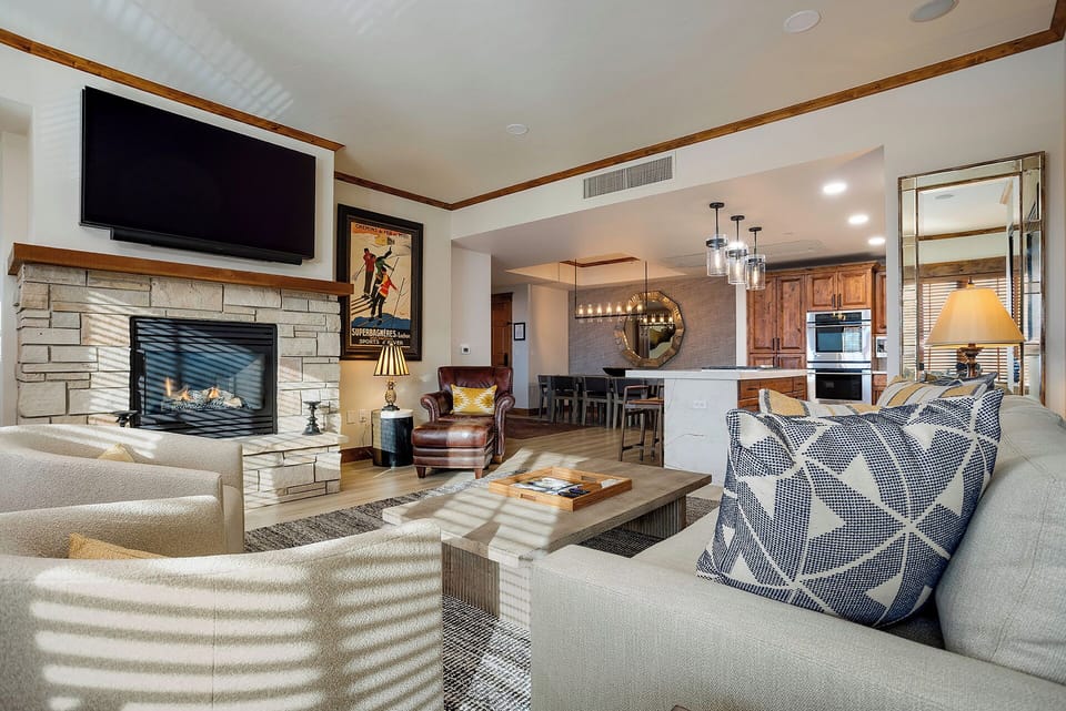 Sink into plush seating by the stone fireplace, where warm wood tones and mountain-inspired décor create your perfect après retreat with open views to the full kitchen.