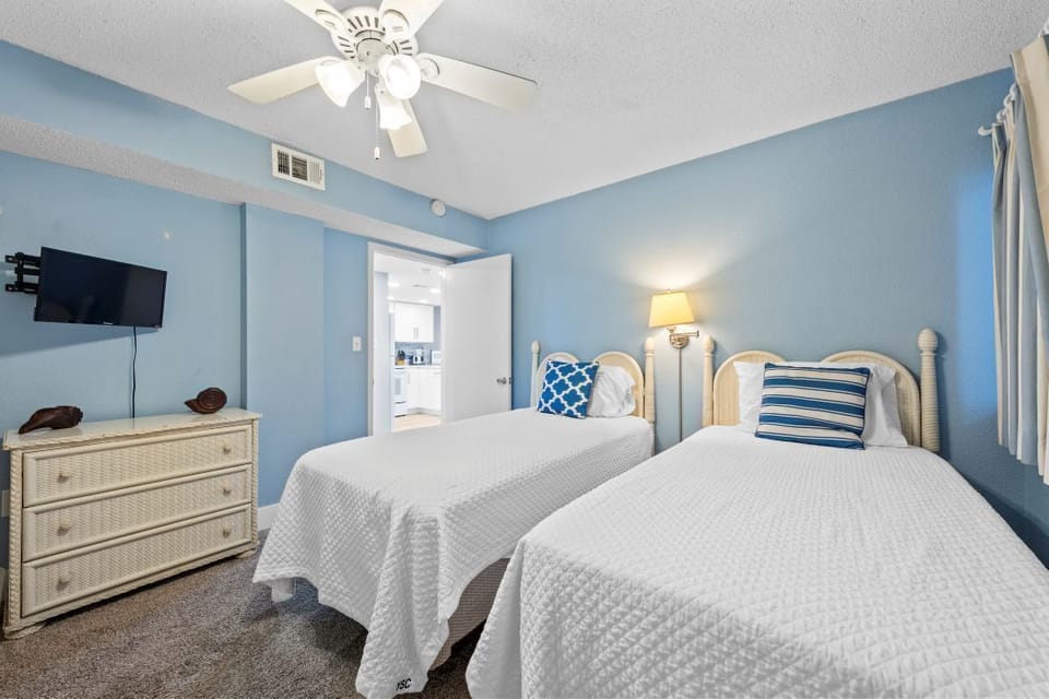 Rest peacefully in your coastal-themed bedroom with twin beds dressed in crisp white linens and cheerful blue accents.