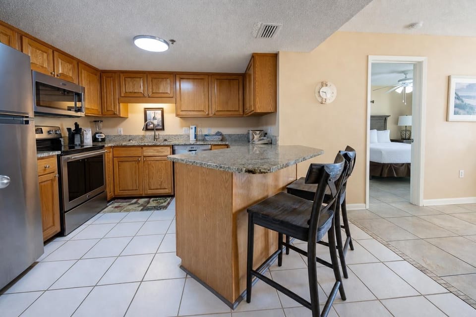 Rich wood cabinetry complements the granite countertops in this kitchen area with a breakfast bar and stainless appliances