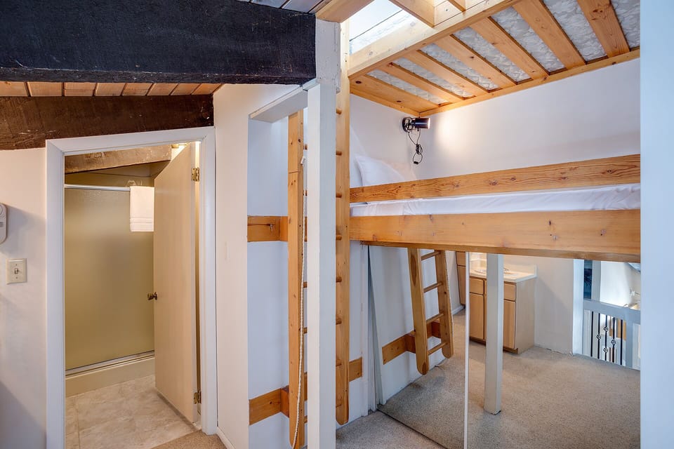 Cozy loft bedroom with sturdy wooden bunk beds and exposed beams creates your perfect mountain retreat sleeping space.