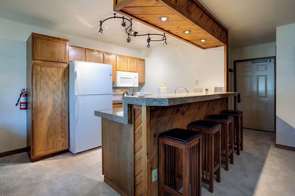 Your fully equipped kitchen features warm wood cabinets, granite counters, and a breakfast bar where you can savor morning coffee or evening conversations.