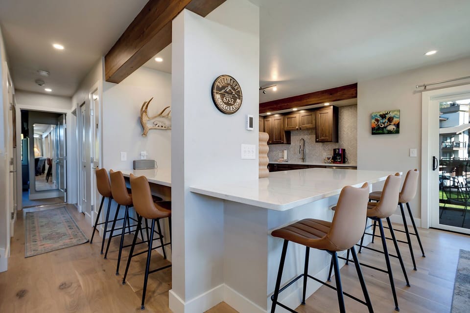Your spacious open kitchen features sleek countertops and warm leather stools, perfect for morning coffee or casual dining together.