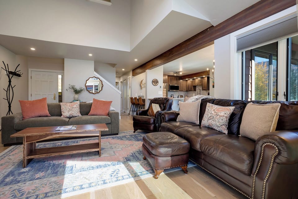 Unwind in your spacious living area with plush leather seating, warm wood beams, and mountain views through expansive windows.