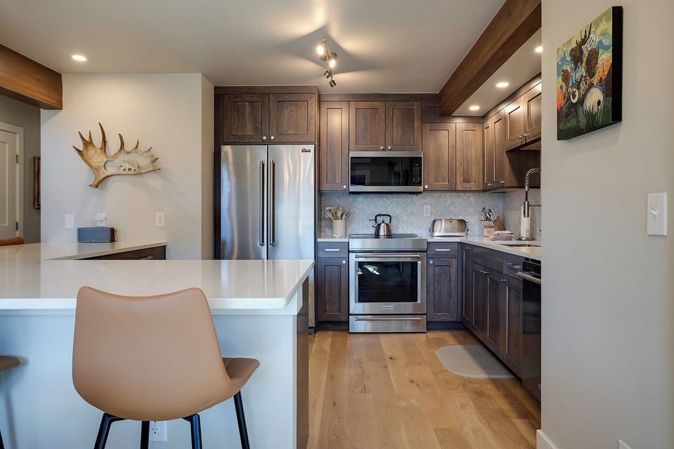 Your stylish kitchen awaits with rich wood cabinetry, stainless steel appliances, and a breakfast bar perfect for morning coffee.