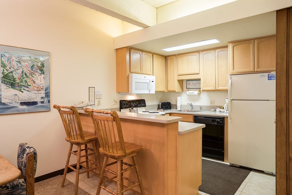 Your fully equipped kitchen features warm wood cabinetry, modern appliances, and a breakfast bar where you can enjoy morning coffee.