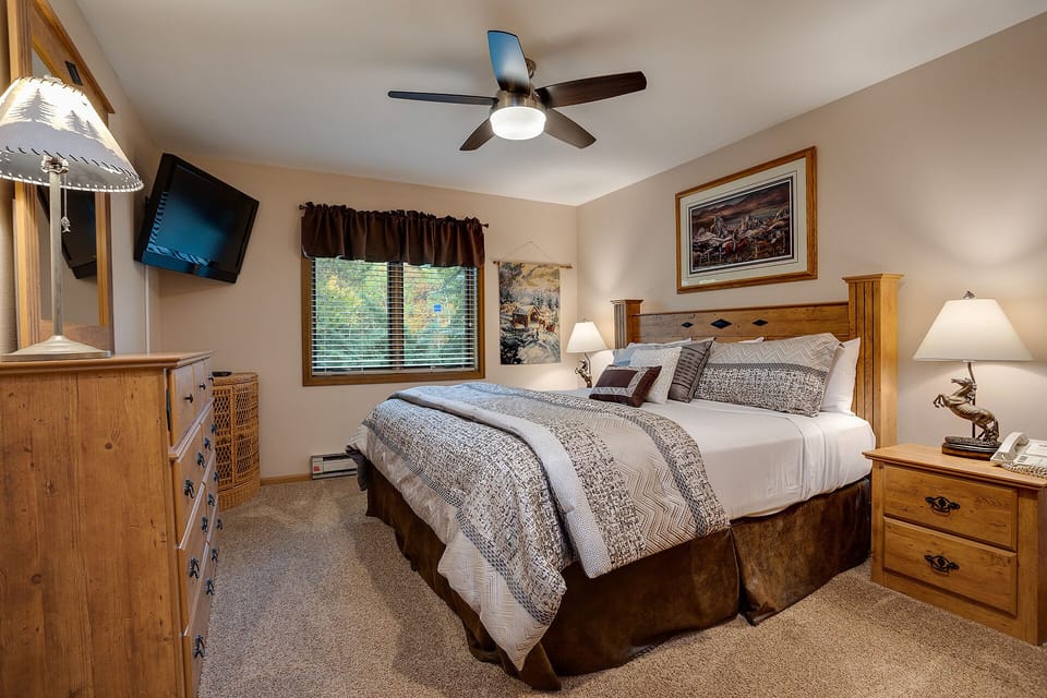 Sink into your cozy king bed under soft linens, surrounded by warm wood tones and homey touches. Your ceiling fan keeps the air fresh while you unwind.
