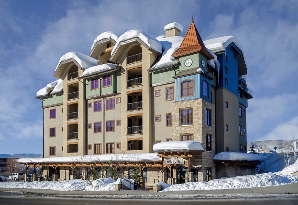 Charming mountain property with distinctive clock tower architecture, nestled amid pristine winter snow and dramatic alpine surroundings.
