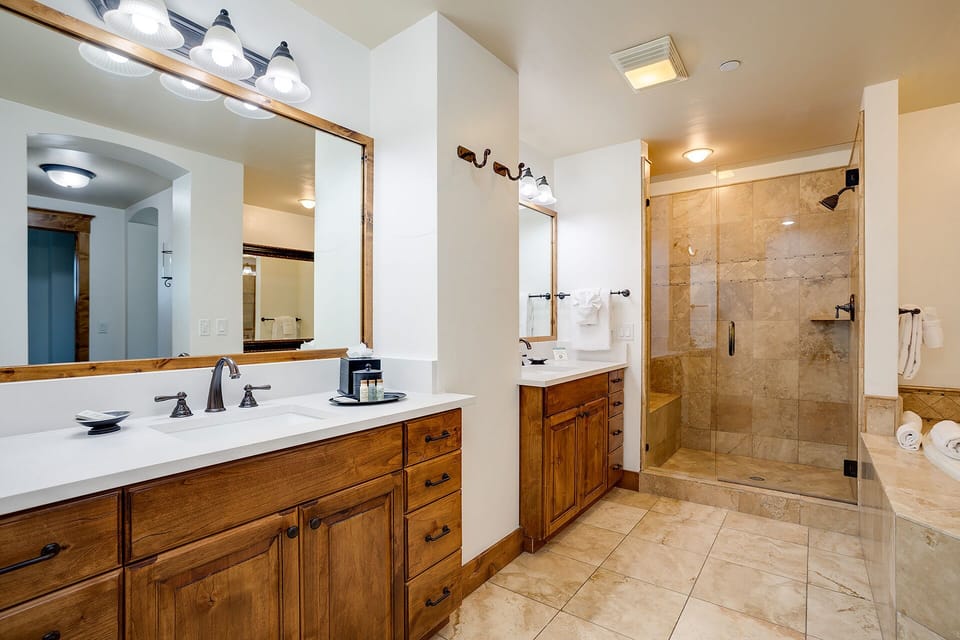 Your private bathroom offers dual vanities, elegant tile work, and a spacious glass-enclosed shower—perfect for refreshing after a day of mountain adventures.