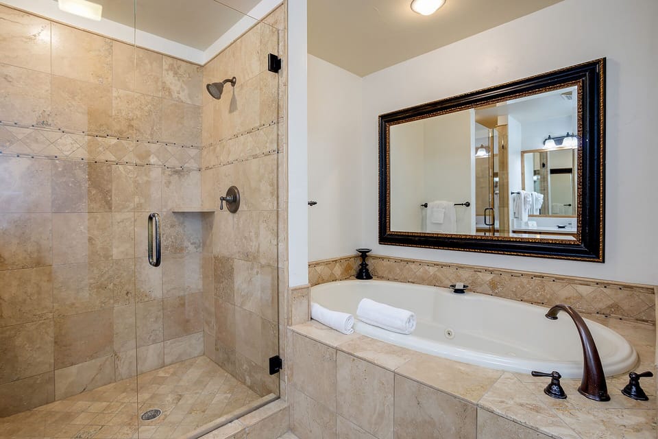 Unwind in your spa-like bathroom featuring a spacious walk-in shower and deep soaking tub. Elegant travertine tile and thoughtful touches create a serene retreat after a day of adventure.