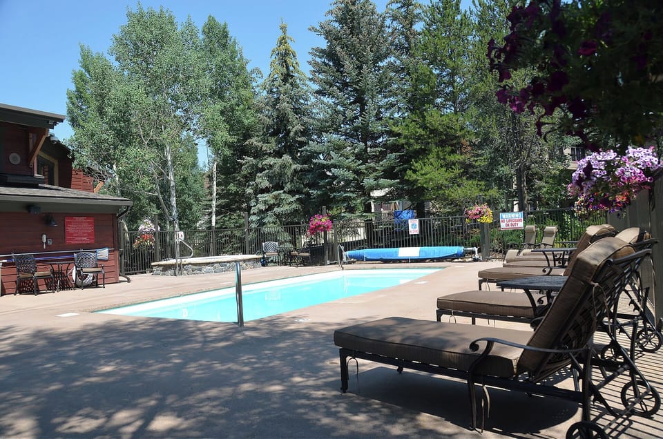 Stretch out on cushioned loungers by your private pool, surrounded by mature trees and vibrant hanging flowers—perfect for sun-soaked afternoons and peaceful relaxation.